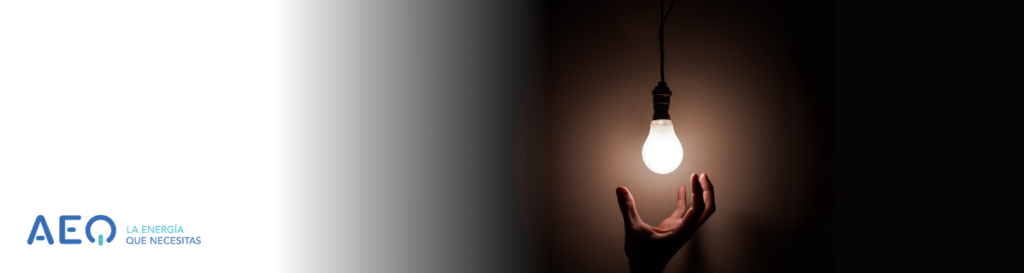 Mano alcanzando bombilla de luz para un texto sobre ahorro de luz.